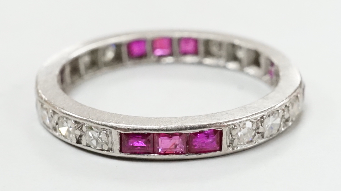 A white metal, ruby and diamond set full eternity ring, size L/M, gross weight 3.1 grams.